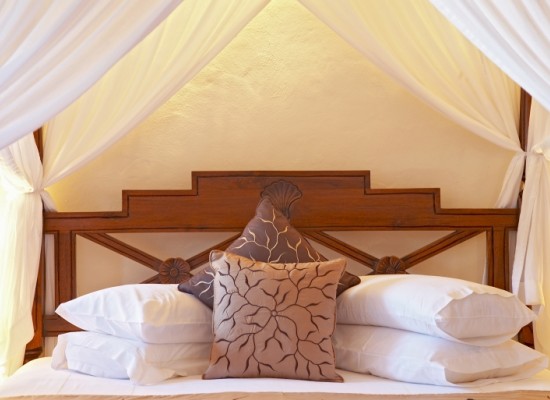 Dřevěná postel s bílými  polštáři